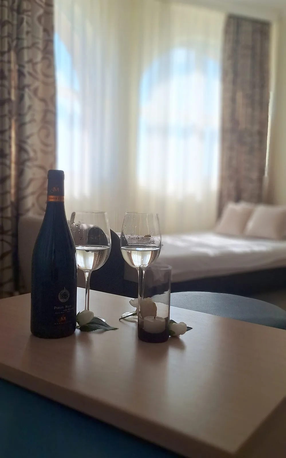 Panorama-Studio: Tischchen mit Flasche und zwei Gläsern vor dem Bett
