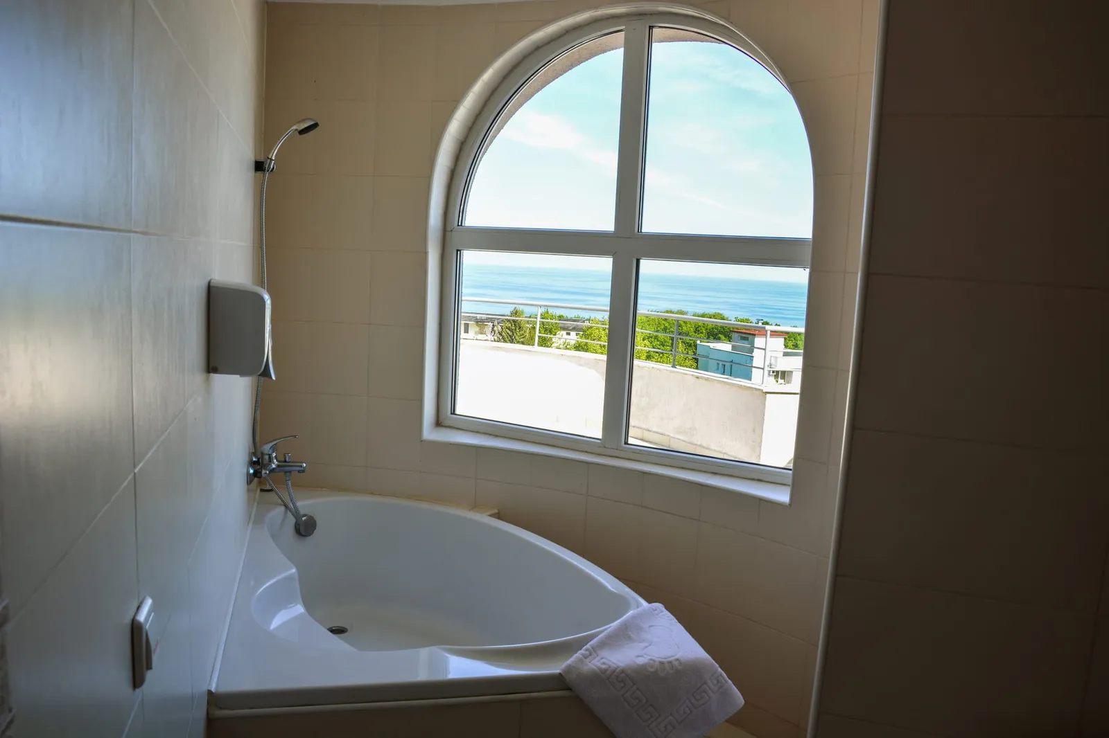 Panorama-Studio: Eckbadewanne und Rundbogenfenster mit Meerblick